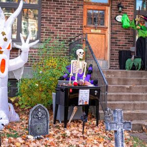 Spooky Halloween decorations featuring an inflatable ghost and skeleton on a porch.