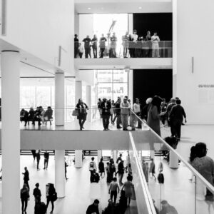 A dynamic black and white image of people in a modern museum setting.