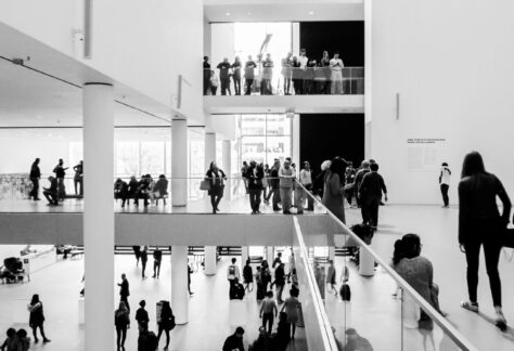 A dynamic black and white image of people in a modern museum setting.